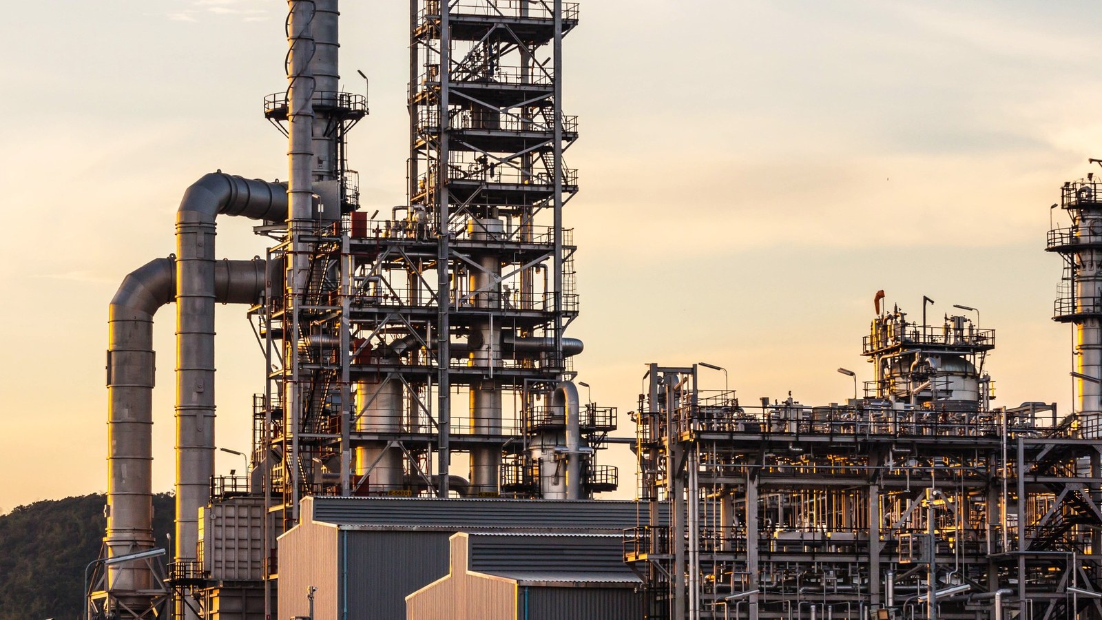 Refinery and coke plant units at dusk, where the carbon chain begins